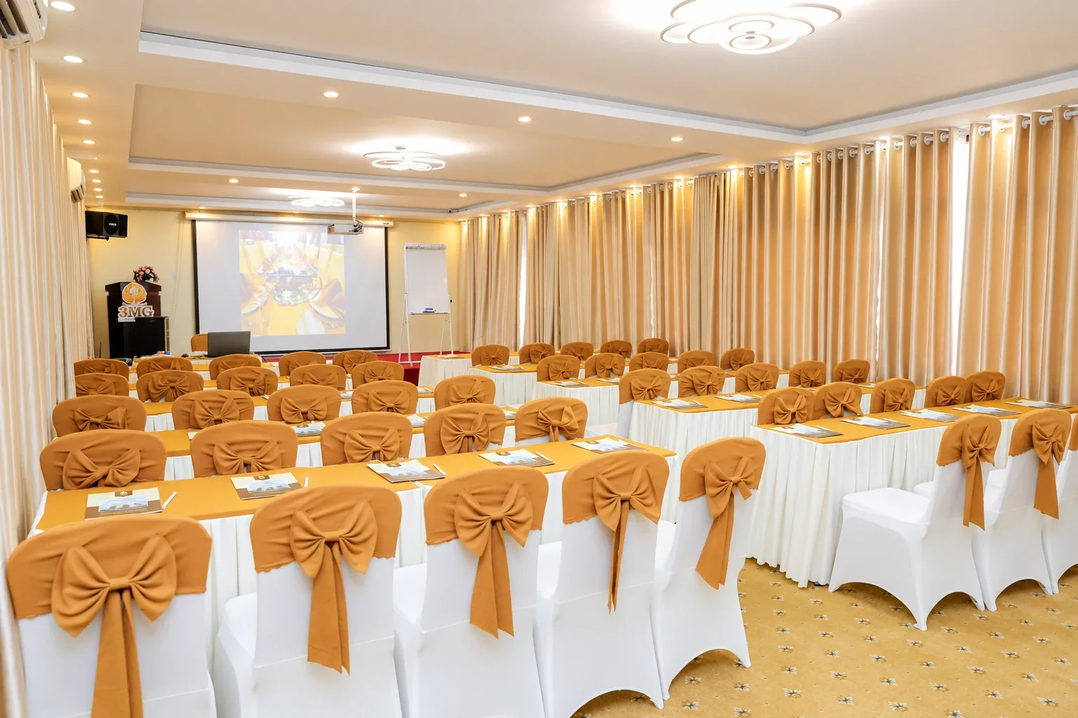 3MG meeting room with tables, stage and projection screen